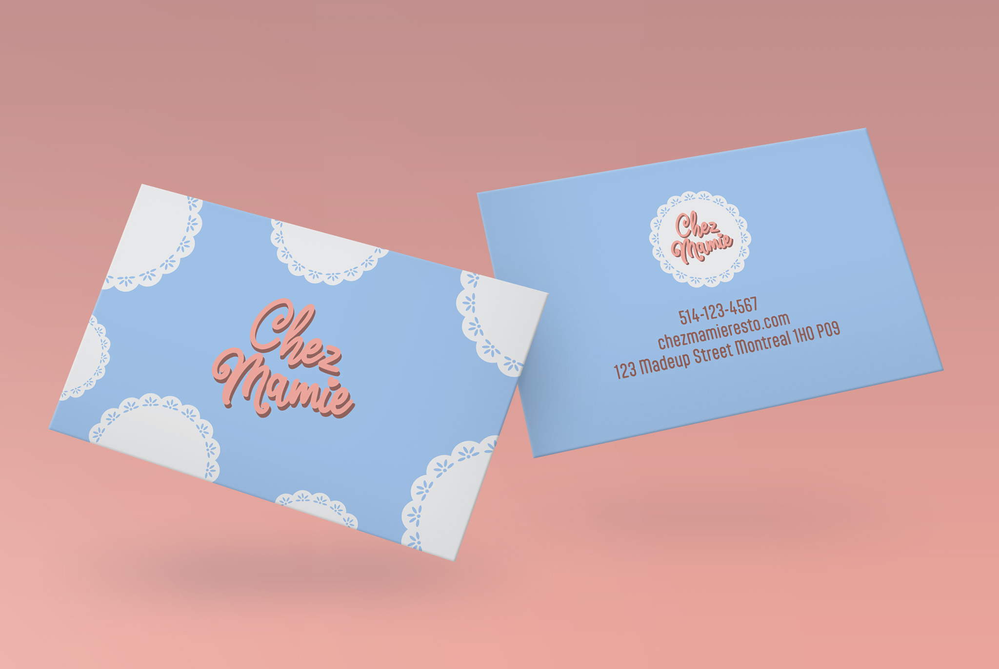 Mockup of blue buisness cards for fictional cafe Chez Mamie on pink background. The front of the card features the logo as well as a doily pattern on the edges. The back of the card features the logo and contact information.